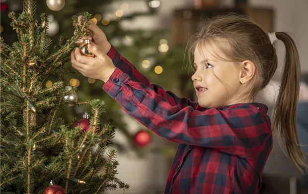 Mädchen schmückt Weihnachtsbaum